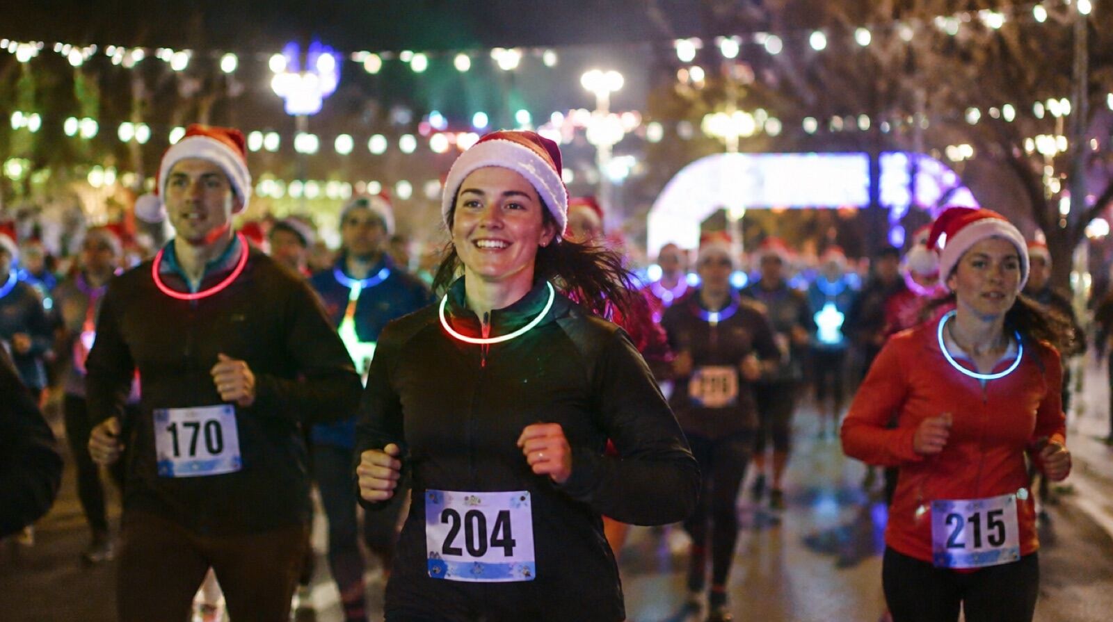 An evening holiday 5K with runners in glow necklaces and Santa hats